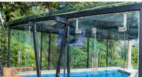Cubierta de cristal y aluminio sobre terraza de madera junto a una alberca