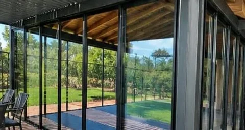Terraza cubierta con recubrimiento de WPC y ventanales de aluminio