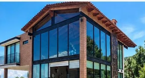 Ventanería integral de aluminio y cristal en fachada de casa de piedra